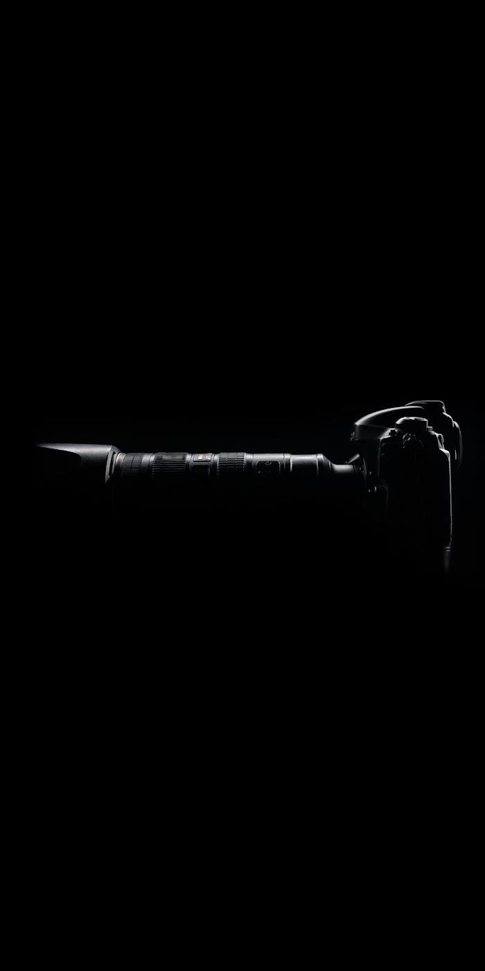 gallery-04 Silhouette of a modern camera with lens against a dark black backdrop.