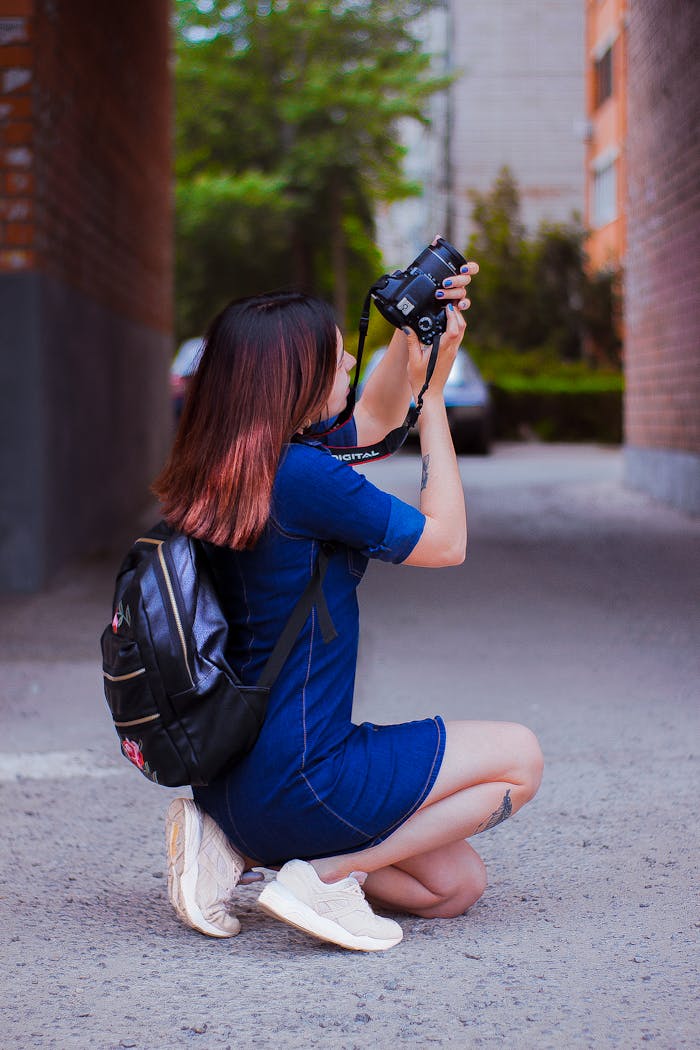 services-03 Female photographer captures urban scenes while kneeling with camera.