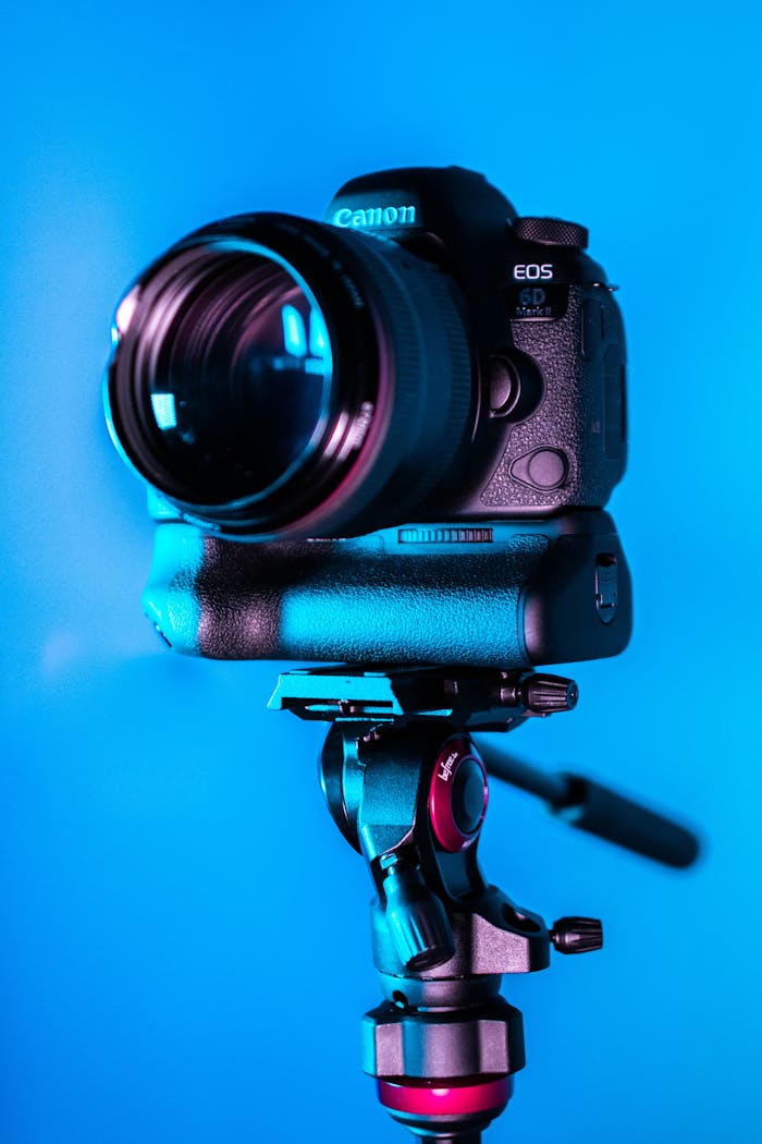 gallery-02 Close-up of a DSLR camera on a tripod with a blue background.