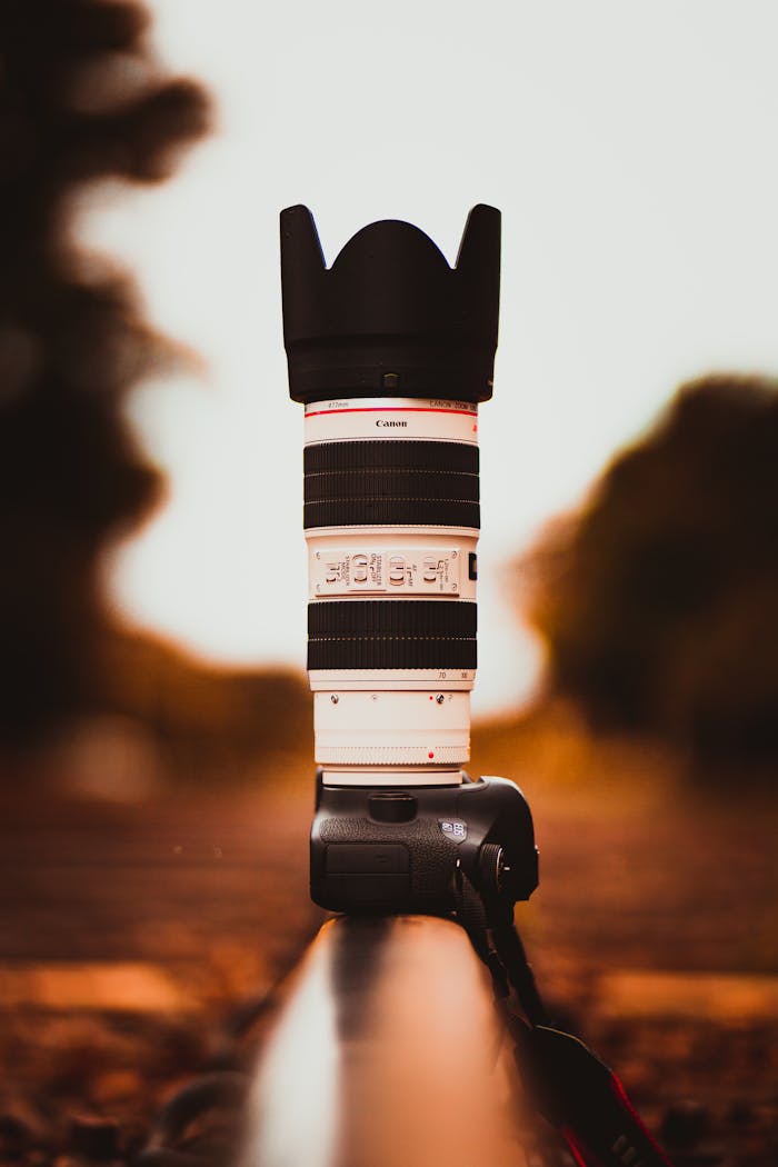 who-we-are Stylish telephoto lens on DSLR camera placed outdoors with blurred bokeh background.